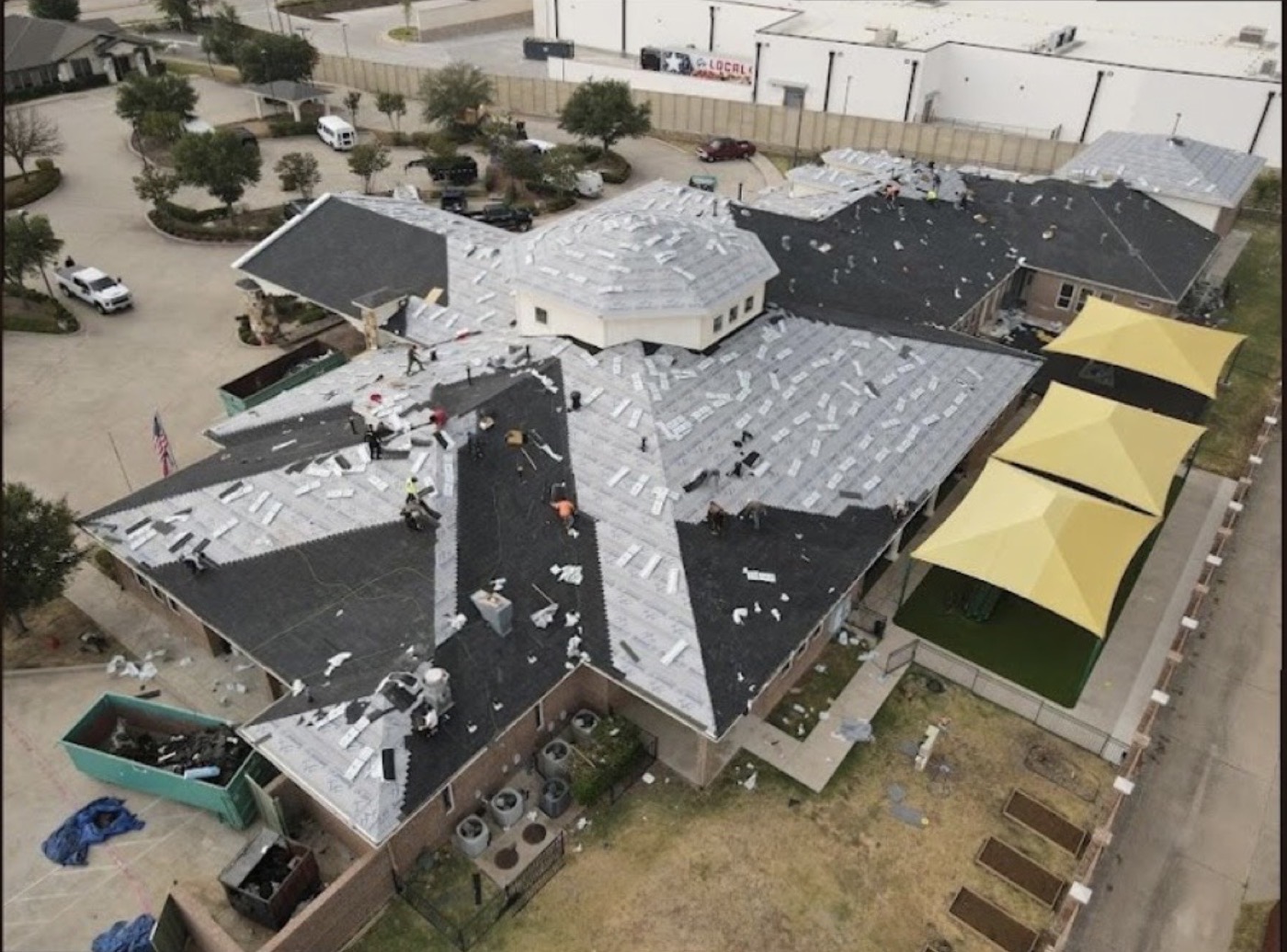 Aerial view of a large-scale roof installation in progress with crew and materials on the roof