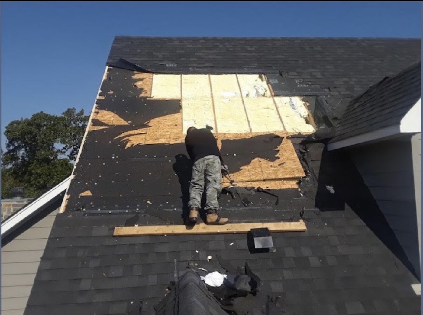 Crew member repairing an isolated damaged section of a shingle roof